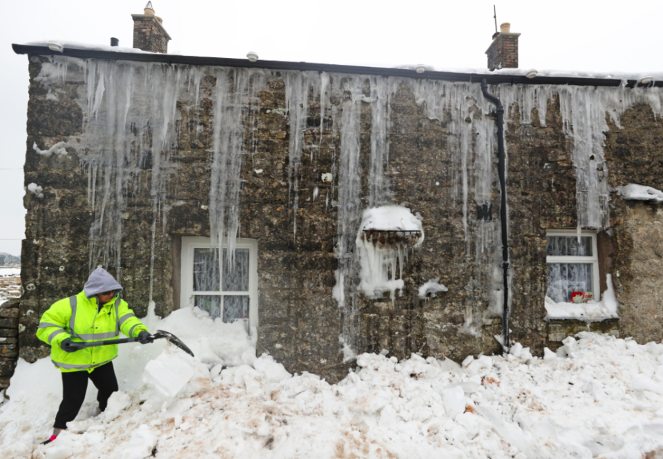 <em>Mags Turnbull from Browfoot Cottage in Bowerdale in Cumbria digs herself out after being snowed in for three days (PA)</em>