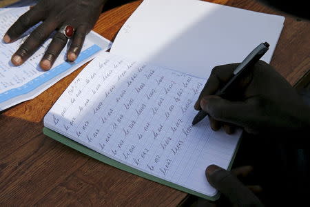 A migrant copies the phrase "the nose" in his notebook after a French course in a makeshift school in "the New Jungle" near Calais, France, August 1, 2015. REUTERS/Pascal Rossignol