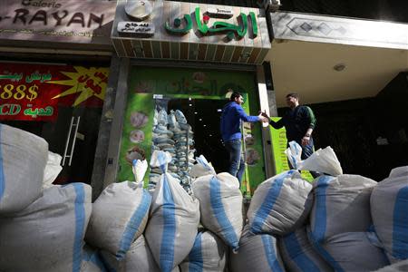 Men greet each other near sandbags, used as protection from future explosions, at a stronghold of Shi'ite group Hezbollah in the southern suburbs of the Lebanese capital Beirut January 30, 2014. REUTERS/Jamal Saidi