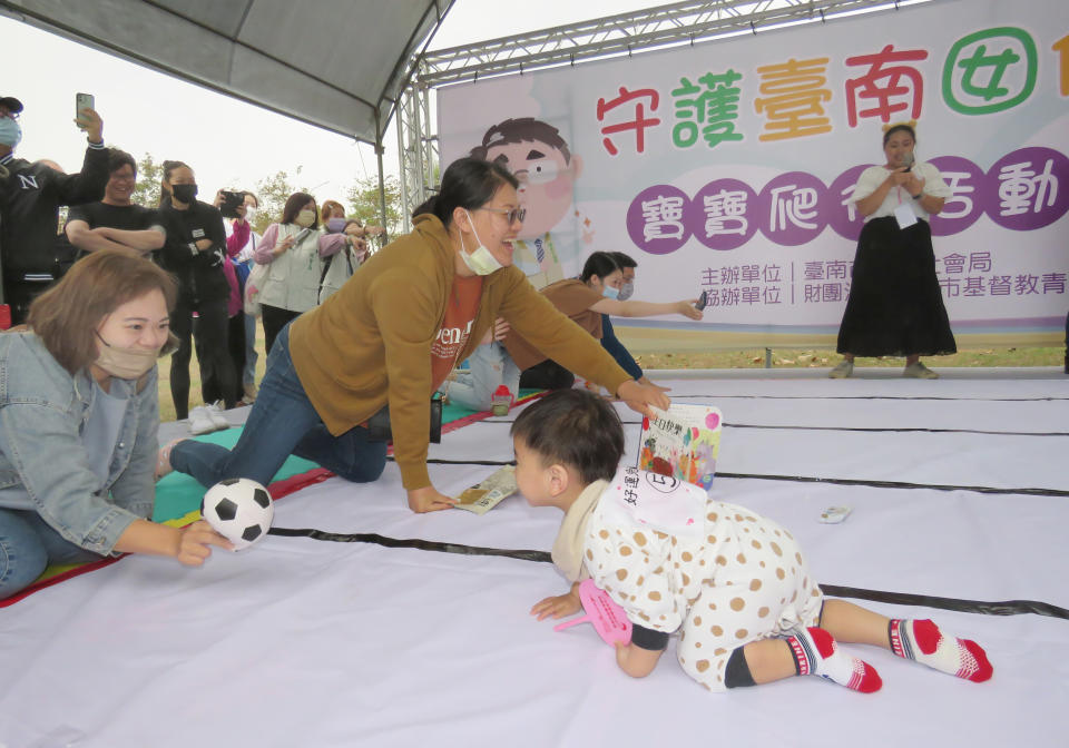 媽媽們手拿嬰兒食品、玩具大聲呼喊，吸引幼童爬到終點。（記者陳治交攝）