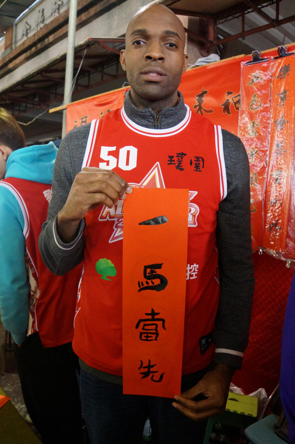 In this Jan. 17, 2014 photo provided by the Pure Youth Construction basketball team, Quincy Davis III holds a Chinese New Year (Year of the Horse) greeting that reads "Being The Lead Horse" in New Taipei City, Taiwan. When the Pure Youth Construction team's owner suggested in 2013 that Davis join Taiwan's national team, he says he found little motivation to keep his U.S. citizenship. "When you think about who I am as a black guy in the U.S., I didn't have opportunities," he says. "You get discriminated against over there in the South. Here everyone is so nice. They invite you into their homes, they're so hospitable. ... There's no crime, no guns. I can't help but love this place." (AP Photo/Pure Youth Construction basketball team)