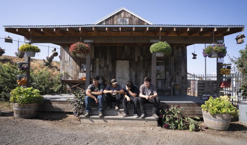 Four people sit on steps in front of a building.