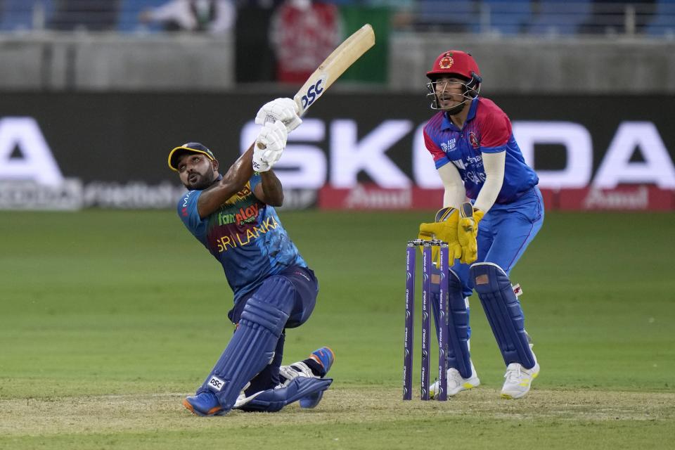 Sri Lanka's Wanindu Hasaranga, left, follows the after playing a shot while Afghanistan's wicketkeeper Rahmanullah Gurbaz watches during the T20 cricket match of Asia Cup between Afghanistan and Sri Lanka, in Dubai, United Arab Emirates, Saturday, Aug. 27, 2022. (AP Photo/Anjum Naveed)