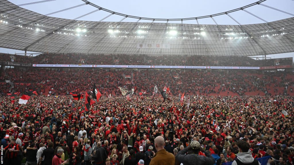 Leverkusen fans celebrate on the pitch