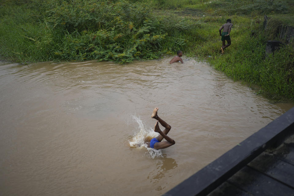 A youth dives into a canal near Ogle International Airport in Georgetown, Guyana, Friday, April 21, 2023. Guyana is in the midst of an oil boom expected to make it the world’s fourth-largest offshore oil producer, raising concerns about potential oil spills and the oil’s contribution to the same climate change that threatens its existence. (AP Photo/Matias Delacroix)