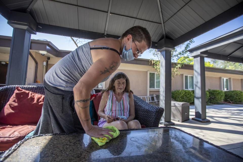 Julia Thomas, left, cleans the outdoor table where Patti Larsen, right, is sitting at the Inn Between.