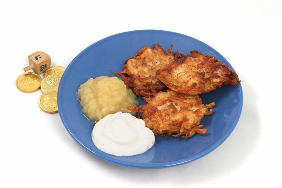 Potato pancakes (latkes) for Hanukah served with applesauce & and sour cream. Isolated with a dreidel & gelt.