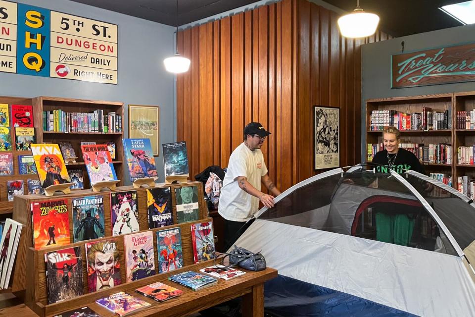 Two people set up a tent inside a bookstore.