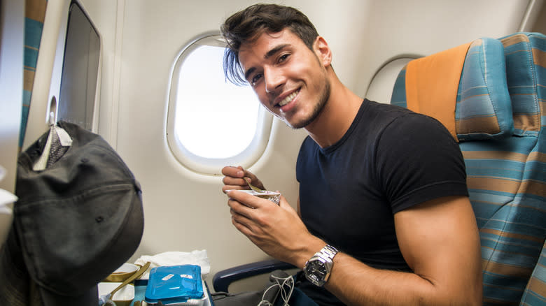 man eating yogurt on airplane