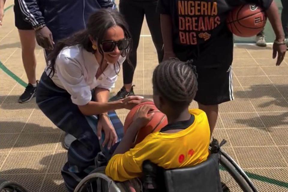 <p>Simon Perry/Instagram</p> Meghan Markle meets a player at Giants of Africa in Lagos