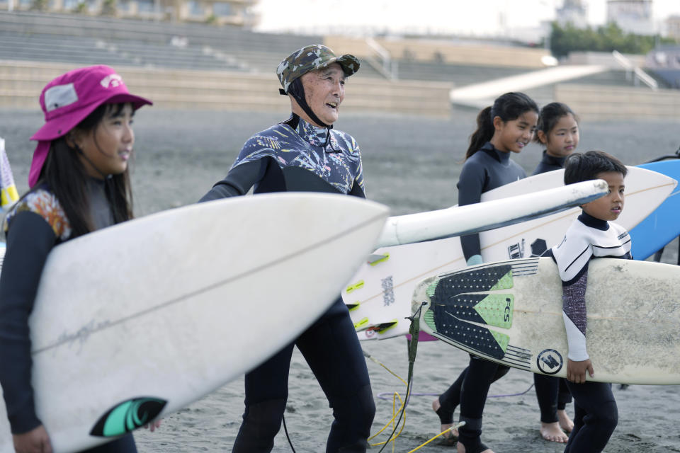 Seiichi Sano, second left, an 89-year-old Japanese man, prepares to surf with young surfers Thursday, March 30, 2023, in Fujisawa, south of Tokyo. Sano, who turns 90 later this year, has been recognized by the Guinness World Records as the oldest male to surf. (AP Photo/Eugene Hoshiko)