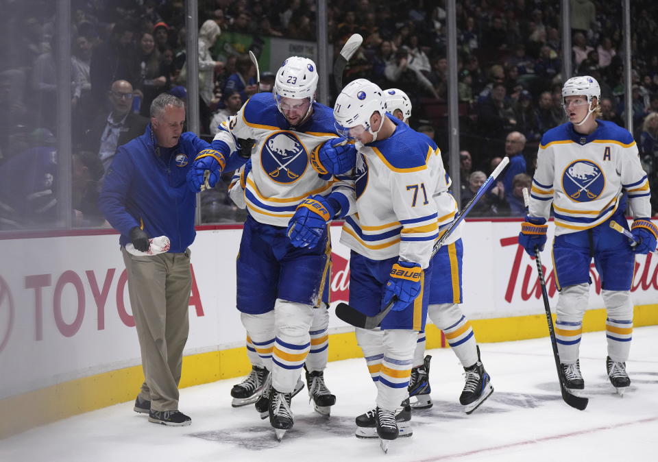 Buffalo Sabres' Mattias Samuelsson (23) is helped up by Victor Olofsson (71), of Sweden, after being injured during the second period of an NHL hockey game against the Vancouver Canucks, in Vancouver, British Columbia, Saturday, Oct. 22, 2022. (Darryl Dyck/The Canadian Press via AP)