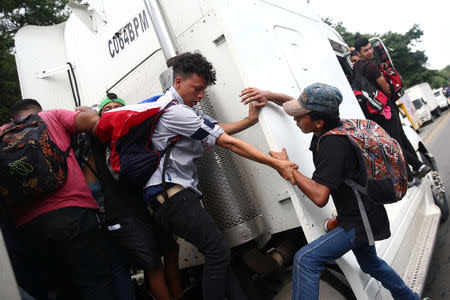 Honduran migrants, part of a caravan trying to reach the U.S., climb on a truck during a new leg of her travel in Zacapa, Guatemala October 17, 2018. REUTERS/Edgard Garrido