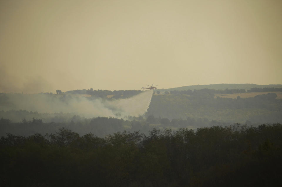 A helicopter drops water over a wildfire in Giannouli village, in the northeastern Evros region, Greece, Thursday, Aug. 31, 2023. Greek authorities have further reinforced firefighting forces in the country's northeast, where a massive blaze in its thirteenth day has flared up once more, triggering authorities to issue alerts to residents in the area to be on standby for possible evacuation. (e-evros.gr via AP)