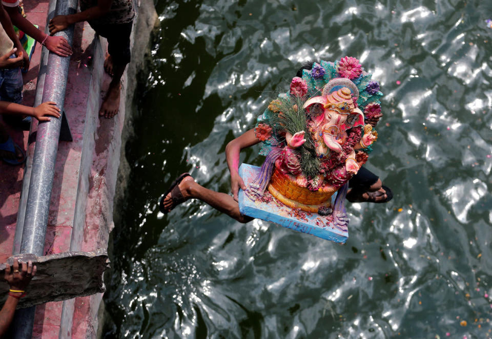 A devotee carrying an idol of the Hindu god Ganesh jumps into the Sabarmati river