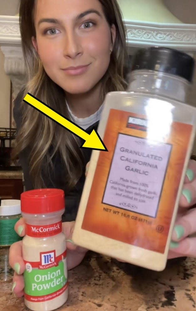 Zoe holding up a bottle of Costco's Kirkland brand garlic powder to the camera, with an arrow pointing to it