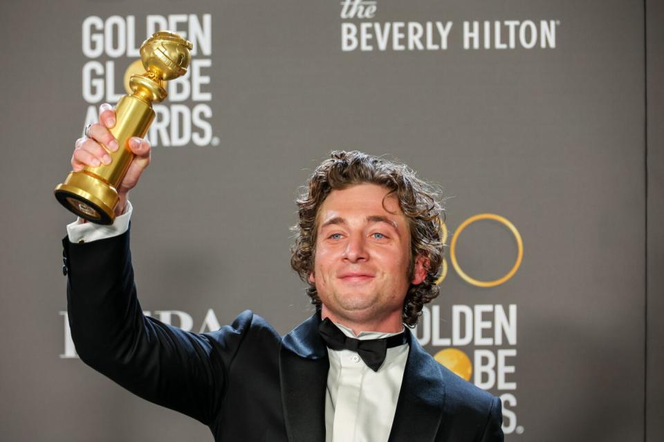 A happy guy hols aloft his Golden Globe award