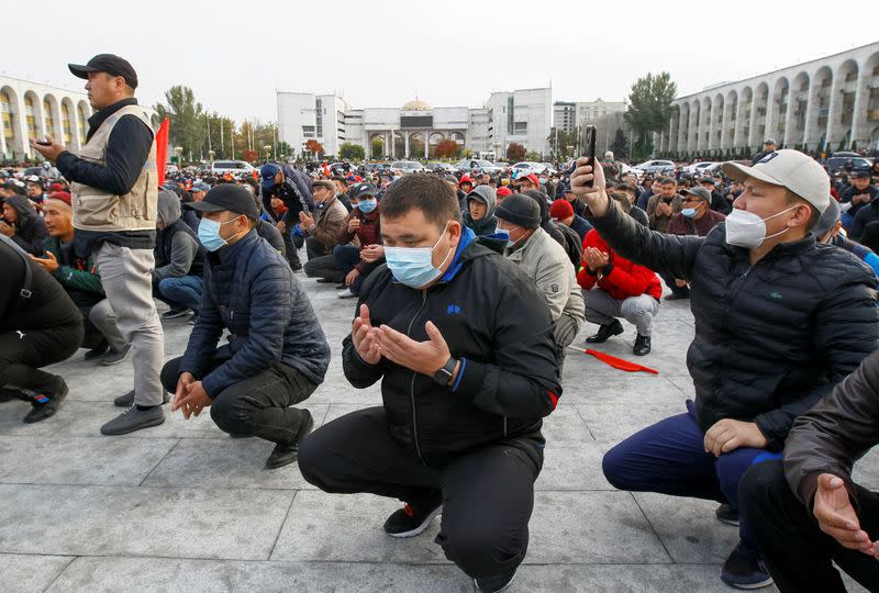 Demonstrators from rival political groups pray during a rally in Bishkek