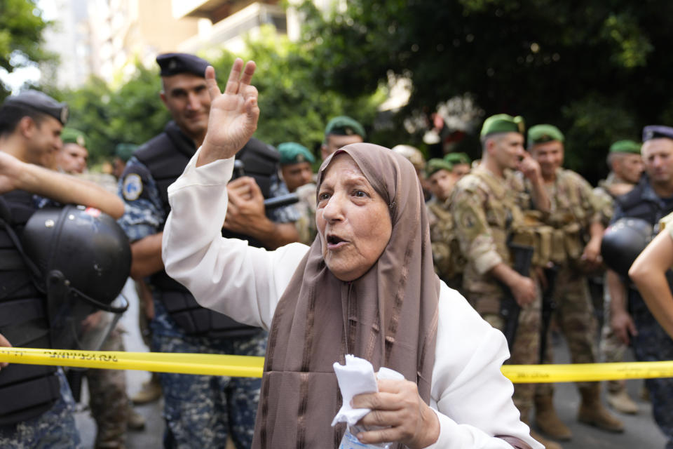 A depositor protests outside a bank where another armed man holds hostages in Beirut, Lebanon, Thursday, Aug. 11, 2022. A Lebanese security official says a man armed with a shotgun has broken into a Beirut bank, holding employees hostage and threatening to set himself ablaze with gasoline unless he receives his trapped saving. (AP Photo/Hussein Malla)