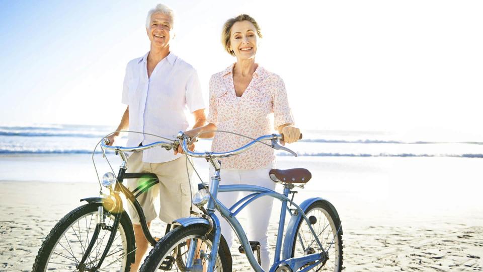 retired couple biking on the beach