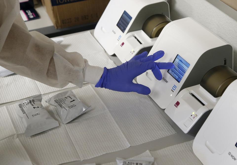 FILE - In this June 15, 2020, file photo, Berto Cortez, a CVS pharmacy technician, shows how COVID-19 tests are processed in a testing area set up by CVS at St. Vincent de Paul medical clinic in Phoenix. The number of deaths per day from the coronavirus in the U.S. has fallen in recent weeks to the lowest level since late March, even as states increasingly reopen for business. But scientists are deeply afraid the trend may be about to reverse itself. (AP Photo/Ross D. Franklin, File)