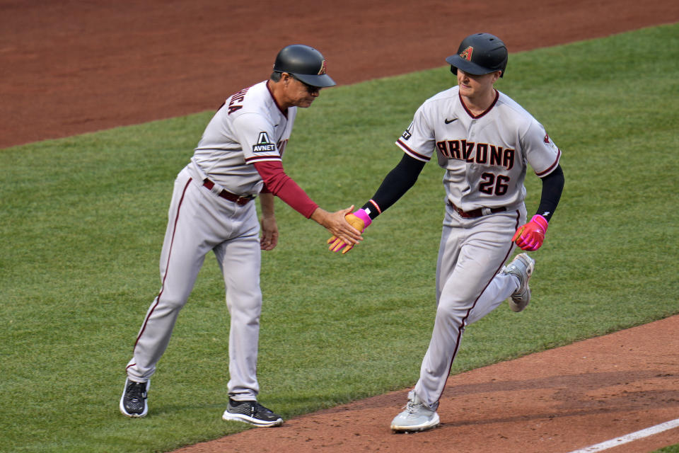 Arizona Diamondbacks' Pavin Smith (26) rounds third base to greetings from coach Tony Perezchica after hitting a two-run home run off Pittsburgh Pirates relief pitcher Robert Stephenson during the seventh inning of a baseball game in Pittsburgh, Saturday, May 20, 2023. (AP Photo/Gene J. Puskar)