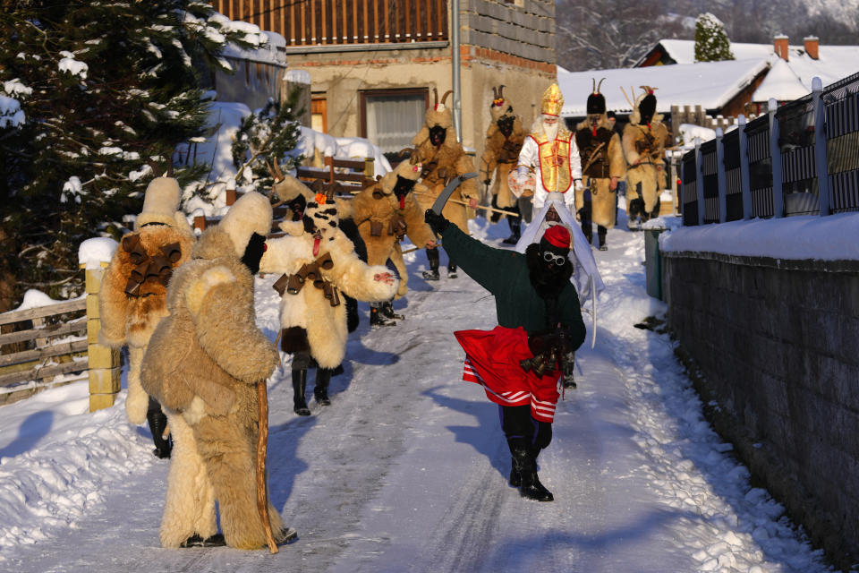 Revelers take part in a traditional St. Nicholas procession in the village of Lidecko, Czech Republic, Monday, Dec. 4, 2023. This pre-Christmas tradition has survived for centuries in a few villages in the eastern part of the country. The whole group parades through village for the weekend, going from door to door. St. Nicholas presents the kids with sweets. The devils wearing home made masks of sheep skin and the white creatures representing death with scythes frighten them. (AP Photo/Petr David Josek)