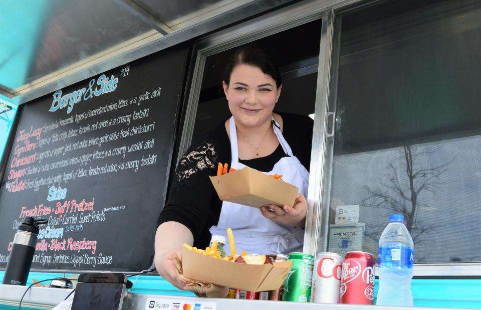 Hallie Abel serves burgers and sides during Food Truck Friday on April 22 in Switchyard Park.