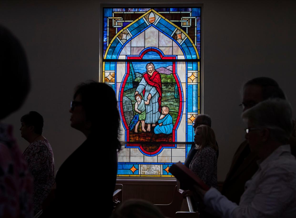 Light shines from a stained glass window depicting Jesus and two children during a Palm Sunday service at  First United Methodist Church in Parsons, Tenn., Sunday, April 10, 2022.