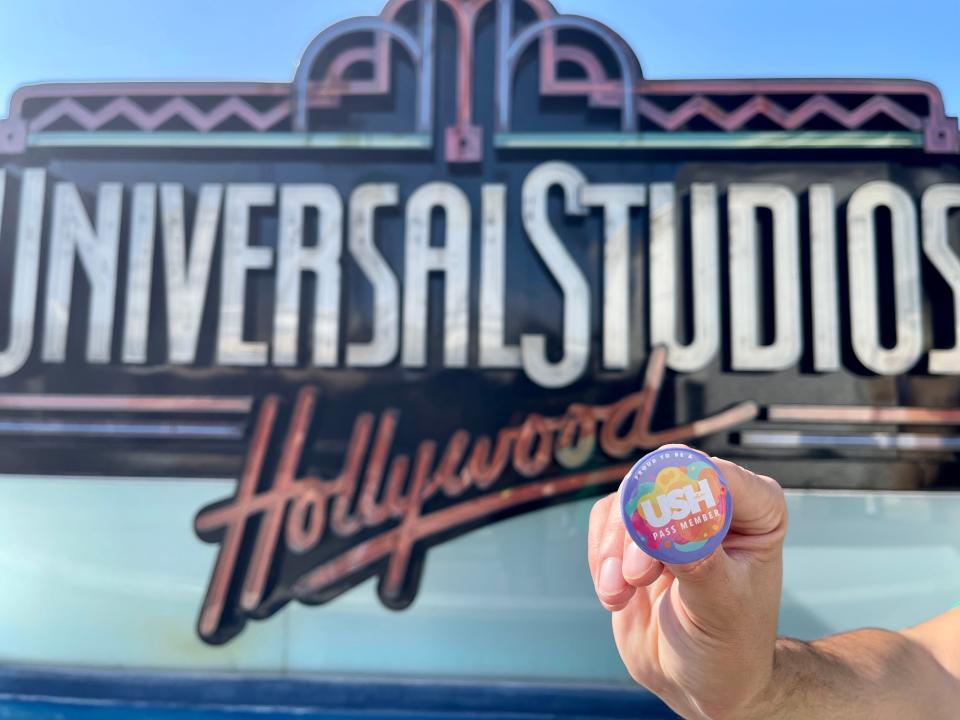 hand holding pass member pin in front of universal sign