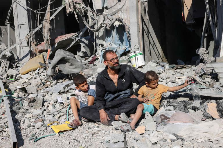 Un hombre palestino con miembros de su familia fuera de un edificio destruido en un ataque aéreo israelí en Rafah, en el sur de la Franja de Gaza, el 12 de octubre de 2023.