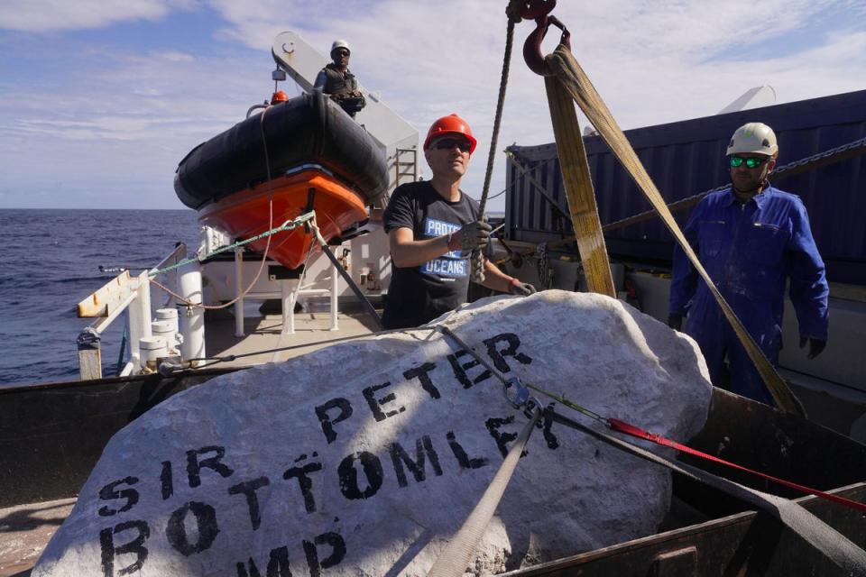 A boulder with Sir Peter Bottomley MP’s name stencilled on is dropped into the western English Channel (Kristian Buus/Greenpeace) (PA Media)