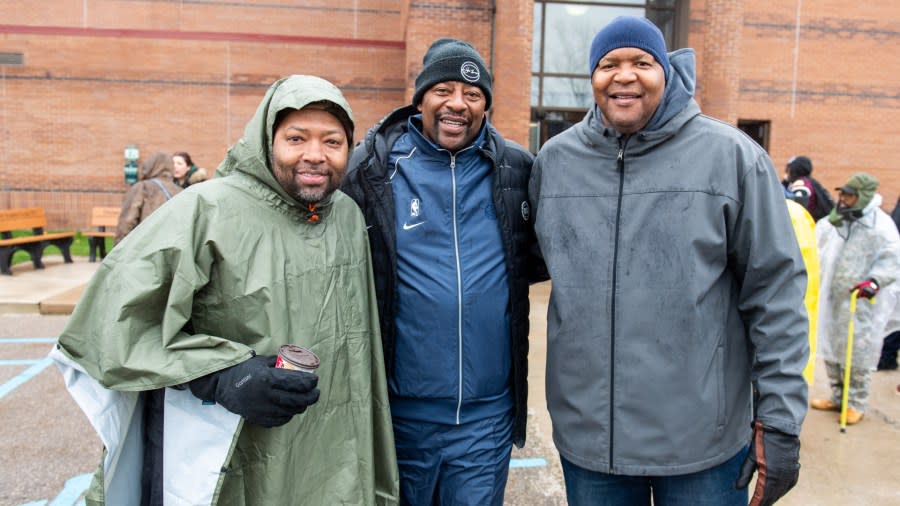 The three men pose together while bundled up in jackets, hats and gloves.