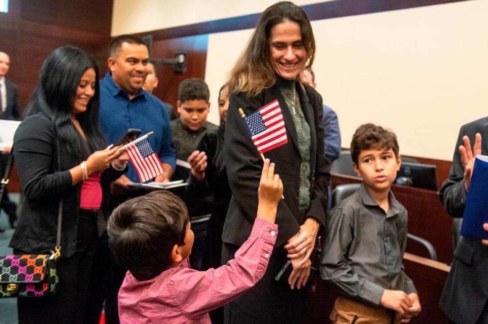 Newly naturalized American citizens wave flags and take photos with their families following a naturalization ceremony at Dan M. Russell Courthouse in Gulfport on Thursday, Oct. 19, 2023.