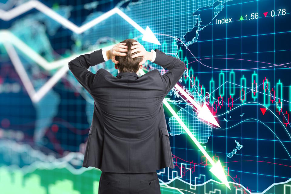 A person panics in front of a plummeting stock price chart.