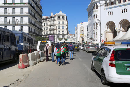 People wear Algerian national flags as they walk past police vehicles in Algiers, Algeria March 4, 2019. REUTERS/Ramzi Boudina