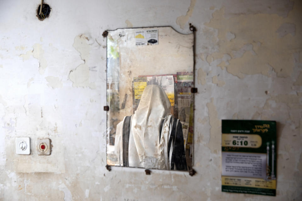 An Ultra-Orthodox Jewish man is reflected in a mirror during a morning prayer next to his house as synagogues are limited to twenty people during a nationwide three-week lockdown to curb the spread of the coronavirus, in Bnei Brak, Israel, Thursday, Sept 24, 2020. Israel moved to further tighten its second countrywide lockdown as coronavirus cases continued to soar. The Cabinet voted to close all nonessential businesses, including open-air markets. Prayers and political demonstrations would be limited to open spaces and no more than 20 people, and participants would not be able to travel more than a kilometer (0.6 miles) from home for either. (AP Photo/Oded Balilty)