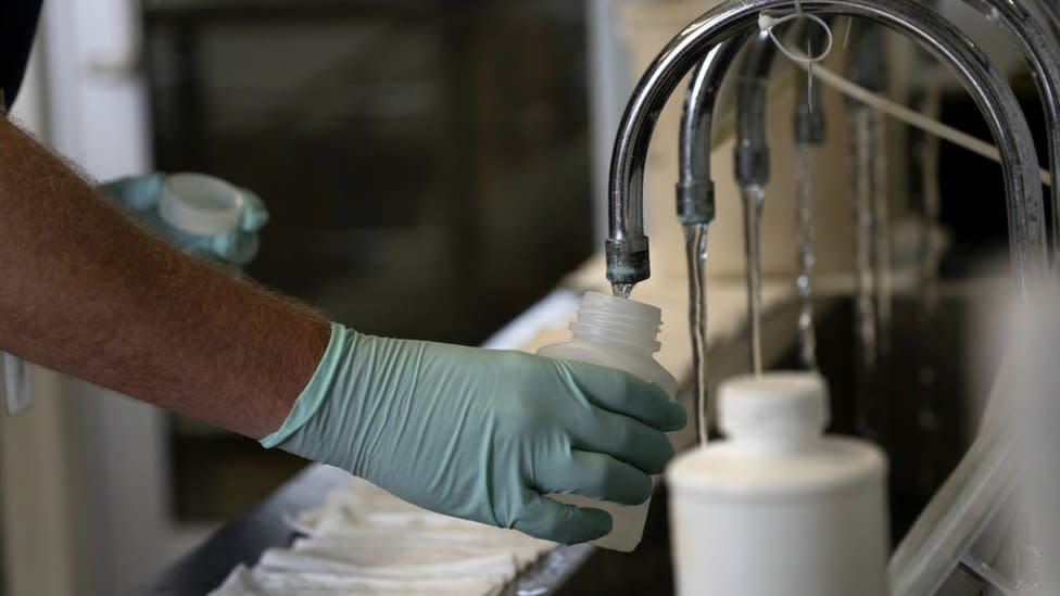 File image of a hand holding a vessel under a tap while water comes out