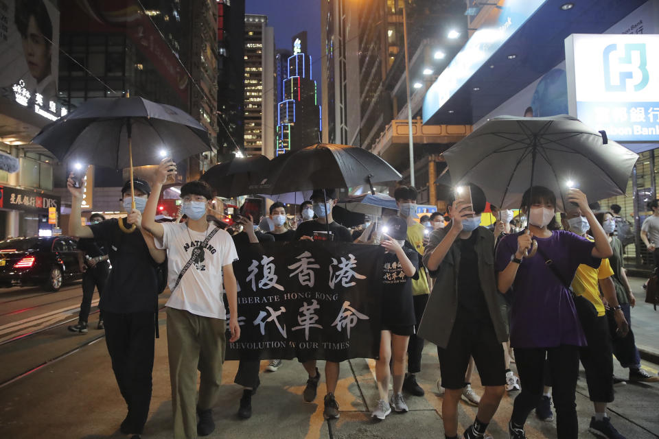 Pro-democracy demonstrators carry a banner reading "Librate Hong Kong, Revolution of our Time" during a protest marking the first anniversary of a mass rally against the now-withdrawn extradition bill in Hong Kong, Tuesday, June 9, 2020. One year ago, a sea of humanity a million people by some estimates marched through central Hong Kong on a steamy afternoon. It was the start of what would grow into the longest-lasting and most violent anti-government movement the city has seen since its return to China in 1997. (AP Photo/Kin Cheung)