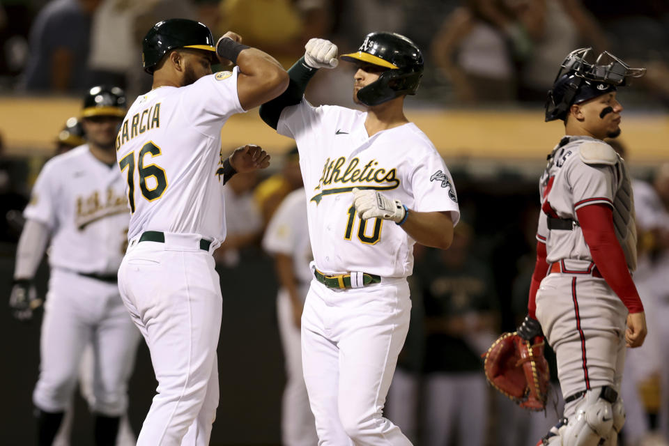 Oakland Athletics' Chad Pinder (10) is congratulated by Dermis Garcia (76) after hitting a three-run home run in front of Atlanta Braves catcher William Contreras, right, during the fifth inning of a baseball game in Oakland, Calif., Tuesday, Sept. 6, 2022. (AP Photo/Jed Jacobsohn)
