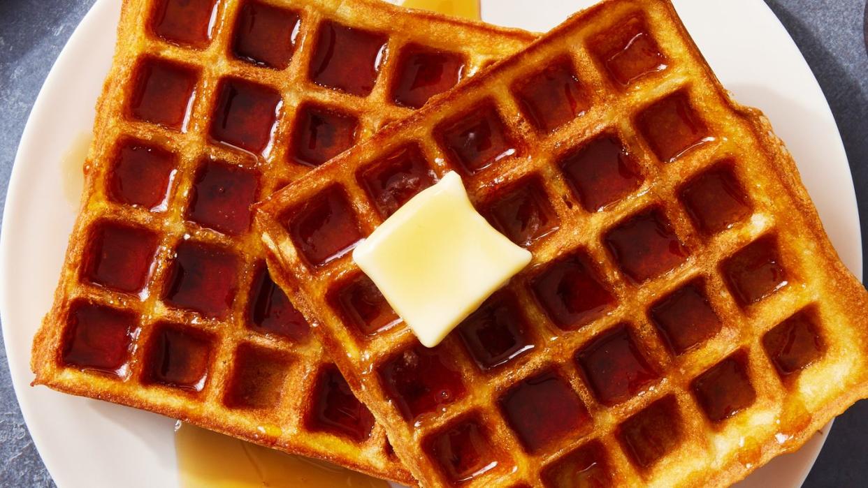 square classic waffles topped with butter and drizzled with maple syrup