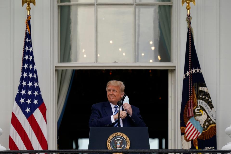 President Donald Trump removes his face mask to speak from the Blue Room Balcony of the White House to a crowd of supporters on Oct. 10, 2020, in Washington.