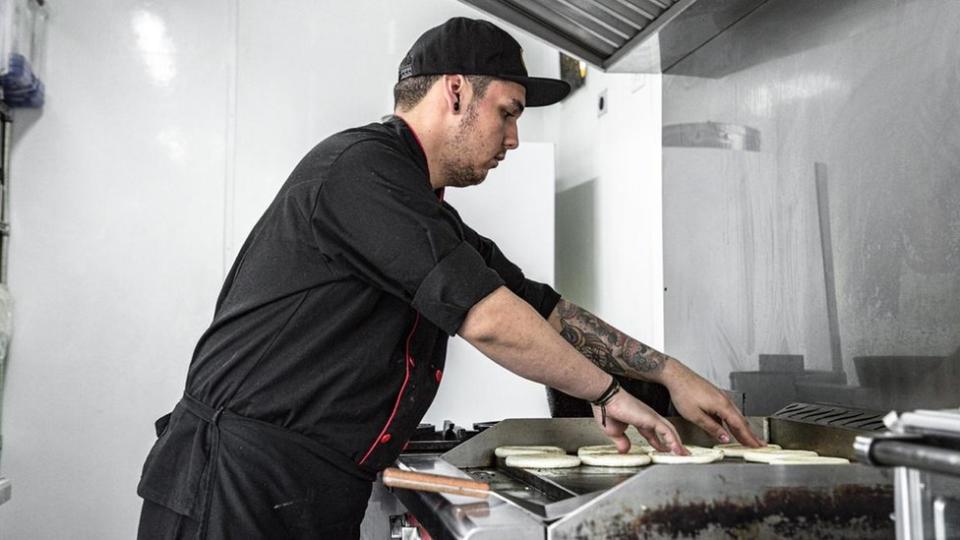 Cocinero tostando arepas en cocina fantasma.