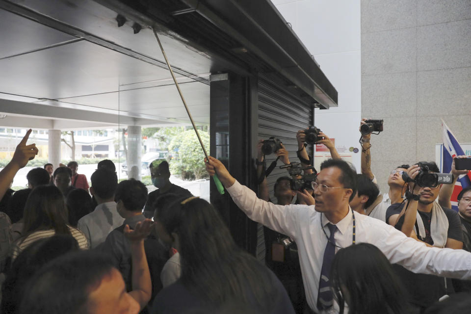 A security guard tries to close the entrance to the Hong Kong Revenue Tower as protesters block people from entering in Hong Kong on Monday, June 24, 2019. Hong Kong has been rocked by major protests for the past two weeks over legislative proposals that many view as eroding the territory's judicial independence and, more broadly, as a sign of Chinese government efforts to chip away at the city's freedoms. (AP Photo/Kin Cheung)