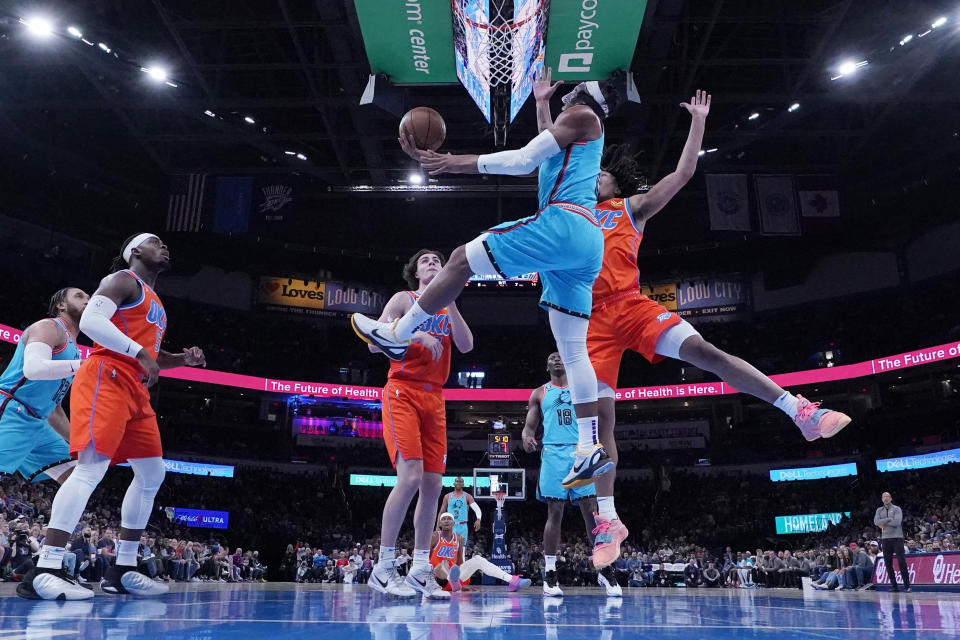 Phoenix Suns forward Josh Okogie, center, shoots in front of guard Luguentz Dort, left, guard Josh Giddey, rear, and forward Jalen Williams, right, in the first half of an NBA basketball game Sunday, March 19, 2023, in Oklahoma City. (AP Photo/Sue Ogrocki)