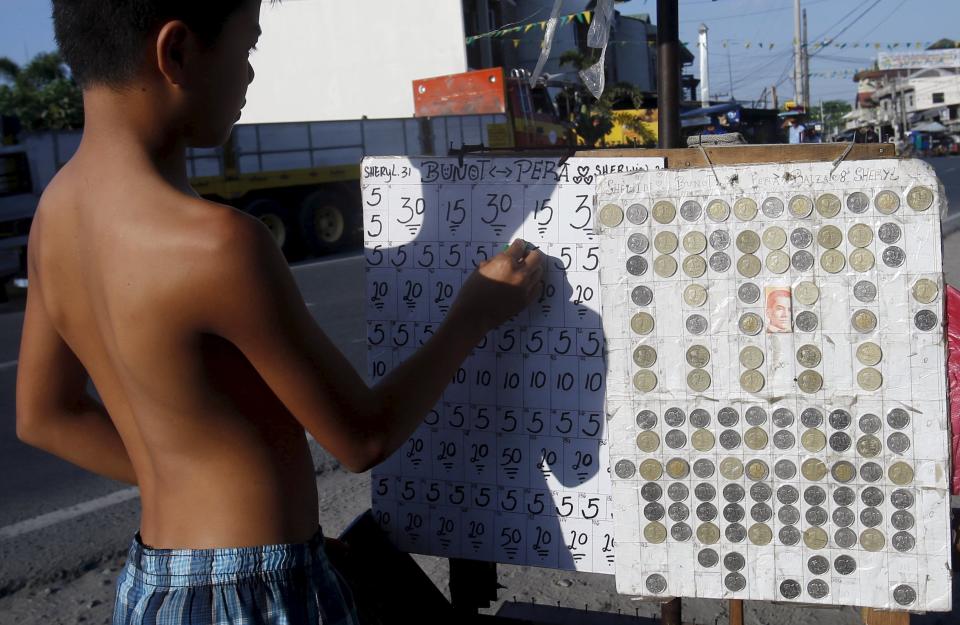 A teenager places bets on a numbers game along a road in San Fernando city, north of Manila, Philippines, March 7, 2015. When paying your final respects for a relative or friend, the last thing you might expect to see at the wake is people placing bets on a card game or bingo. Not in the Philippines. Filipinos, like many Asians, love their gambling. But making wagers on games such as "sakla", the local version of Spanish tarot cards, is particularly common at wakes because the family of the deceased gets a share of the winnings to help cover funeral expenses. Authorities have sought to regulate betting but illegal games persist, with men and women, rich and poor, betting on anything from cockfighting to the Basque hard-rubber ball game of jai-alai, basketball to spider races. Many told Reuters photographer Erik De Castro that gambling is only an entertaining diversion in a country where two-fifths of the population live on $2 a day. But he found that some gamble every day. Casino security personnel told of customers begging to be banned from the premises, while a financier who lends gamblers money at high interest described the dozens of vehicles and wads of land titles given as collateral by those hoping lady luck would bring them riches. REUTERS/Erik De Castro PICTURE 28 OF 29 FOR WIDER IMAGE STORY "HIGH STAKES IN MANILA". SEARCH "BINGO ERIK" FOR ALL IMAGES.