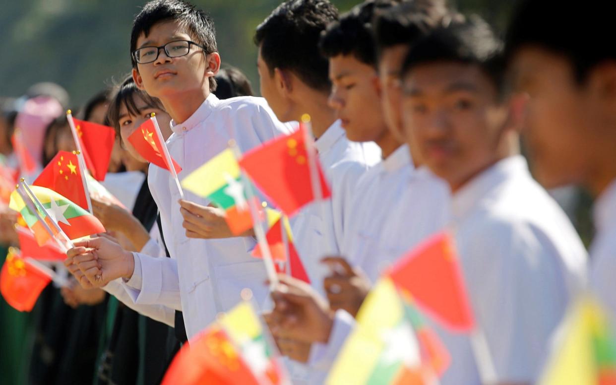 Myanmar students hold Myanmar and Chinese flags as they prepare to welcome Chinese President Xi Jinping outside of the airport in Naypyitaw - REUTERS