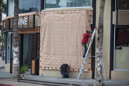 People cover the facade of a store in Cabo San Lucas as Hurricane Lorena churns close to the southern tip of Mexico's Baja California peninsula