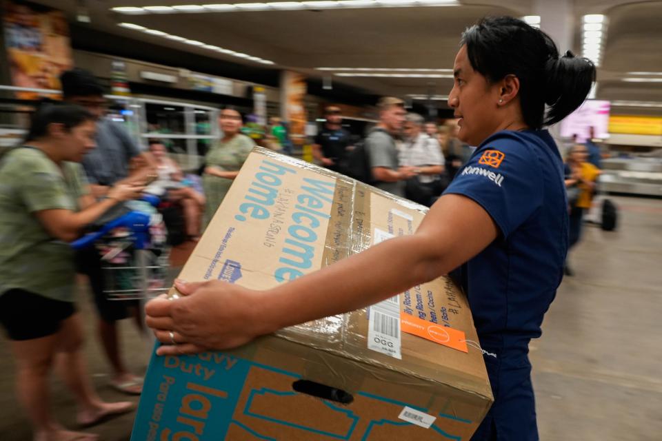 Eileen Domingo, 36, carries aid packages from the mainland U.S. at Kahului Airport. The packages include items such as toiletries and clothing for victims of the devastating Maui wildfires. Domingo, who is from the Lahaina area, says, “I can count the amount of homes left standing.”