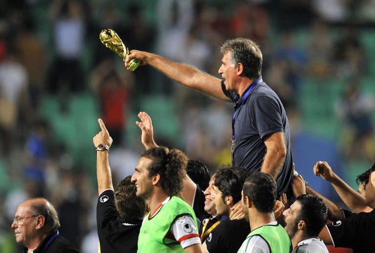 Iran's head coach Carlos Queiroz, holding a mock trophy, celebrates with his players after their World Cup Asian qualifier football match against South Korea in Ulsan, some 300 km southeast of Seoul, on June 18, 2013. Iran won the match 1-0